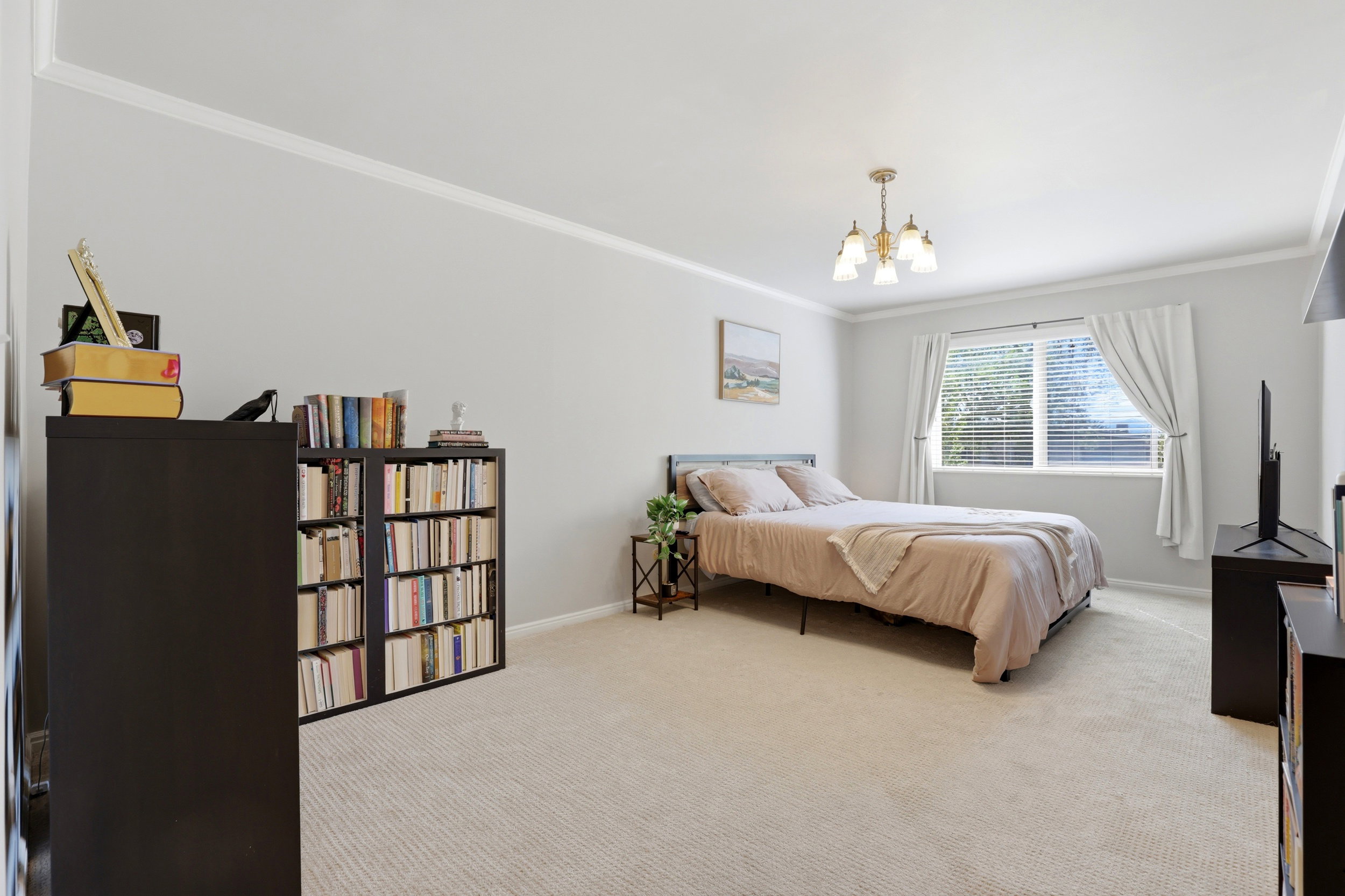Bedroom with light colored carpet, ornamental molding, and suspended lighting