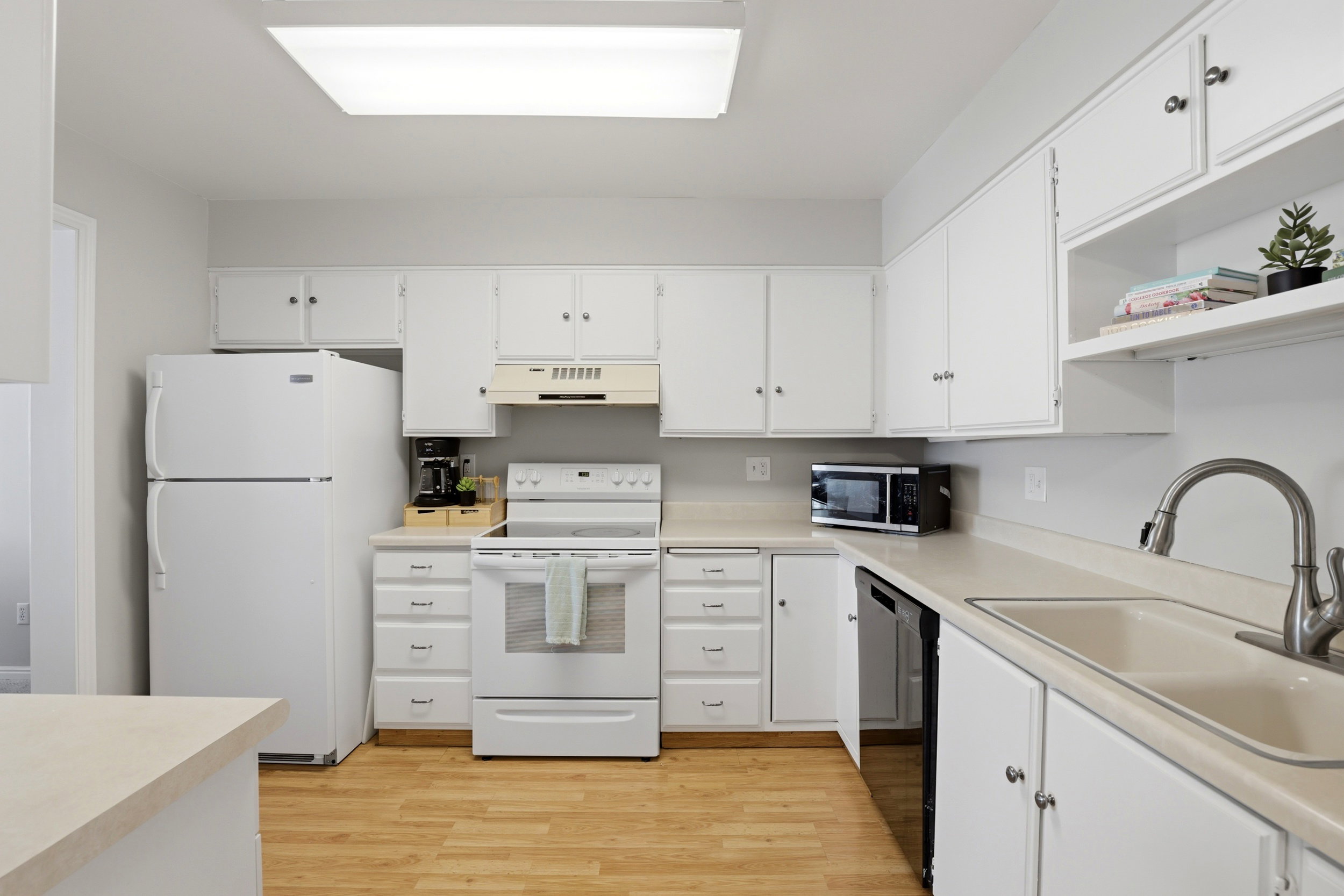 Kitchen featuring light countertops, white appliances, and white cabinets