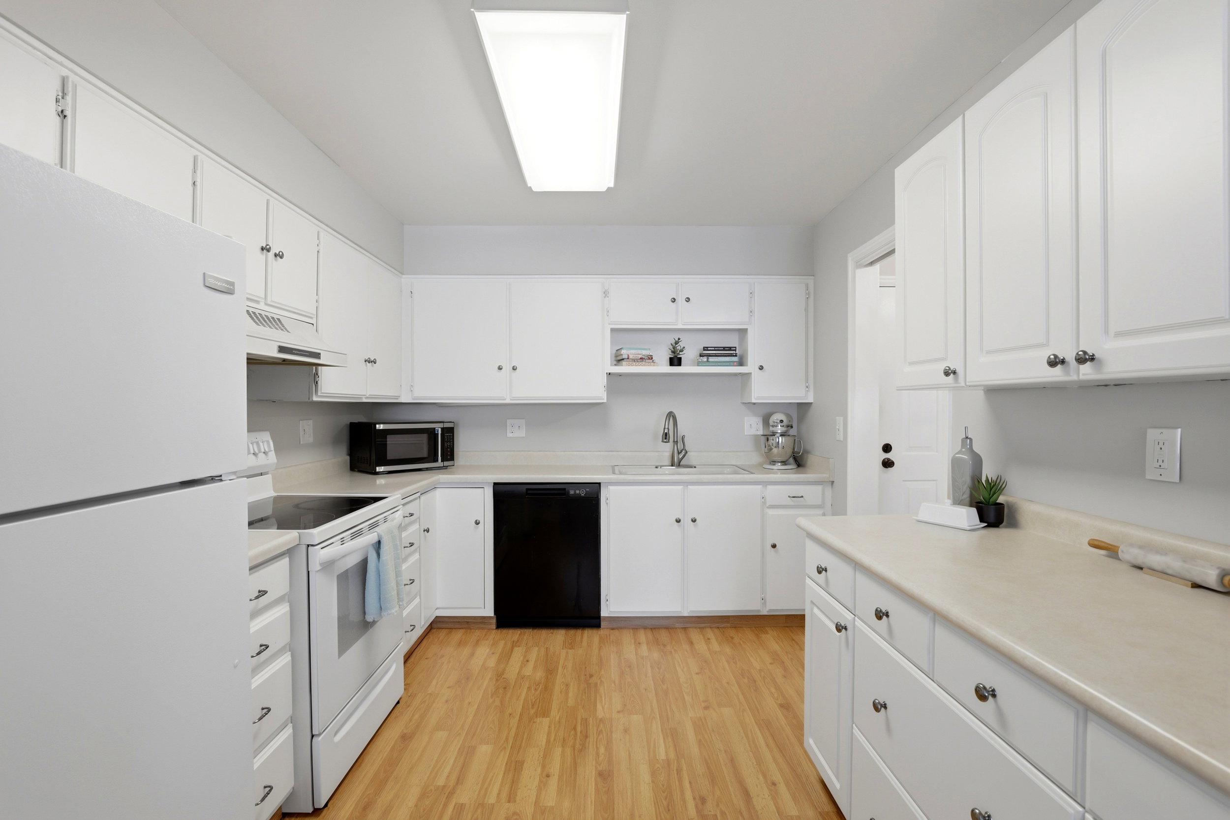 Kitchen with white appliances, light countertops, white cabinetry, light wood finished floors, and open shelves