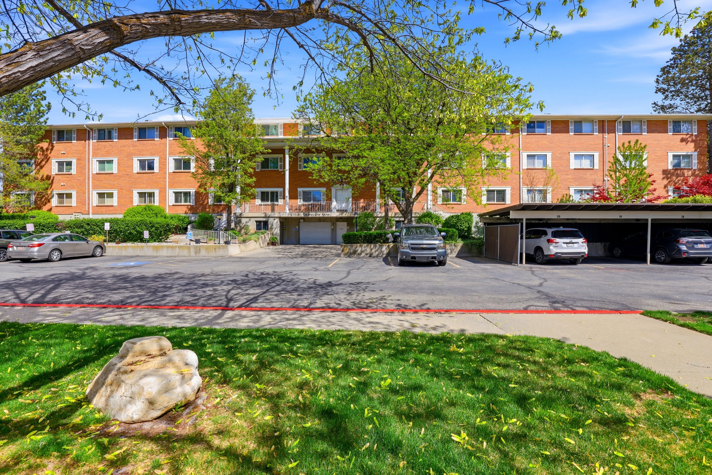 View of apartment building / complex featuring covered parking