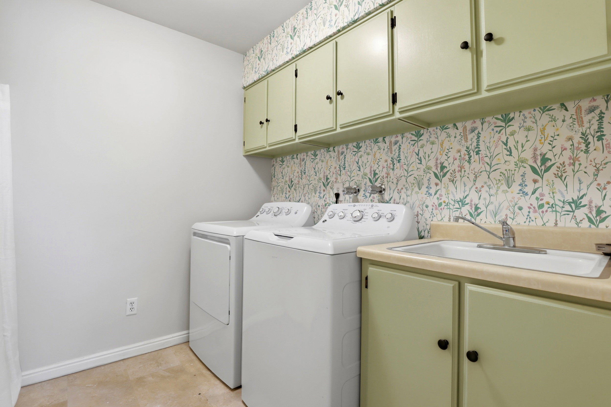 Laundry area with cabinet space, independent washer and dryer, and wallpapered walls