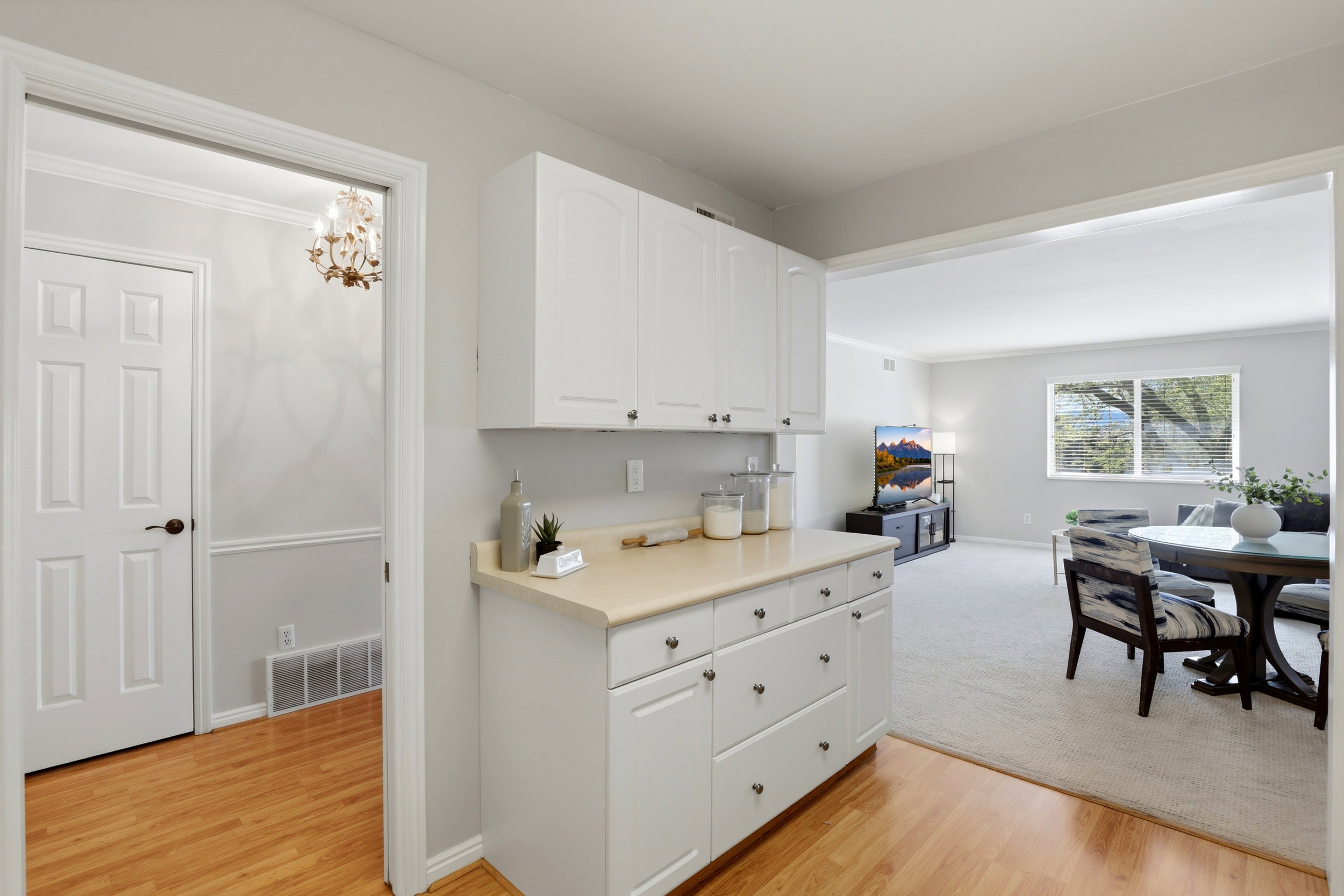 Kitchen with light countertops, white cabinetry, light wood-style floors, open floor plan, and ornamental molding