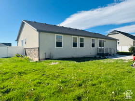 Back of property with stucco siding, stone siding, and a fenced backyard