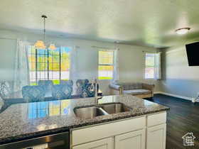 Kitchen featuring open floor plan, dark stone counters, white cabinets, and a textured ceiling