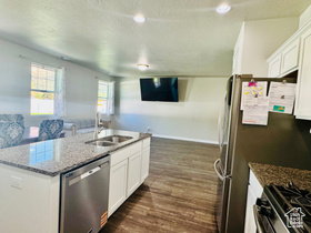 Kitchen with white cabinetry, dark stone countertops, a kitchen island with sink, stainless steel appliances, and a textured ceiling