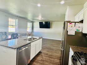 Kitchen with white cabinetry, dark stone countertops, a kitchen island with sink, stainless steel appliances, and a textured ceiling
