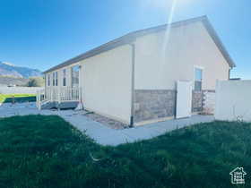 View of property exterior with stucco siding, stone siding, and a mountain view
