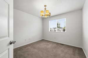 Empty room featuring carpet and a chandelier