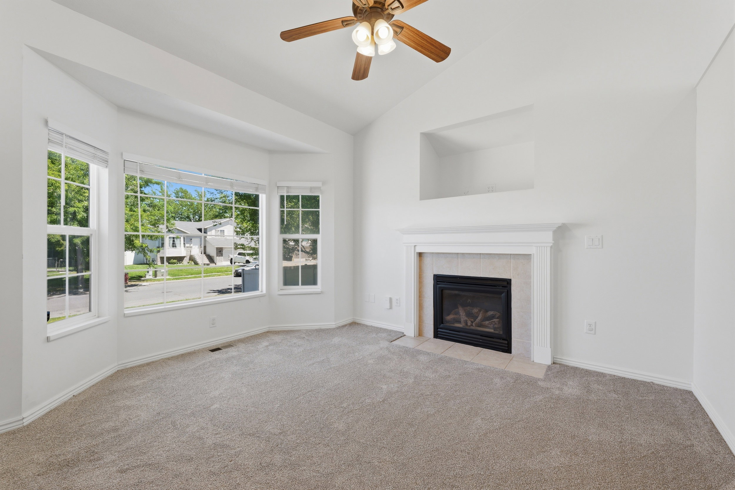 Bright living area featuring a bay window, vaulted ceiling, and a ceiling fan