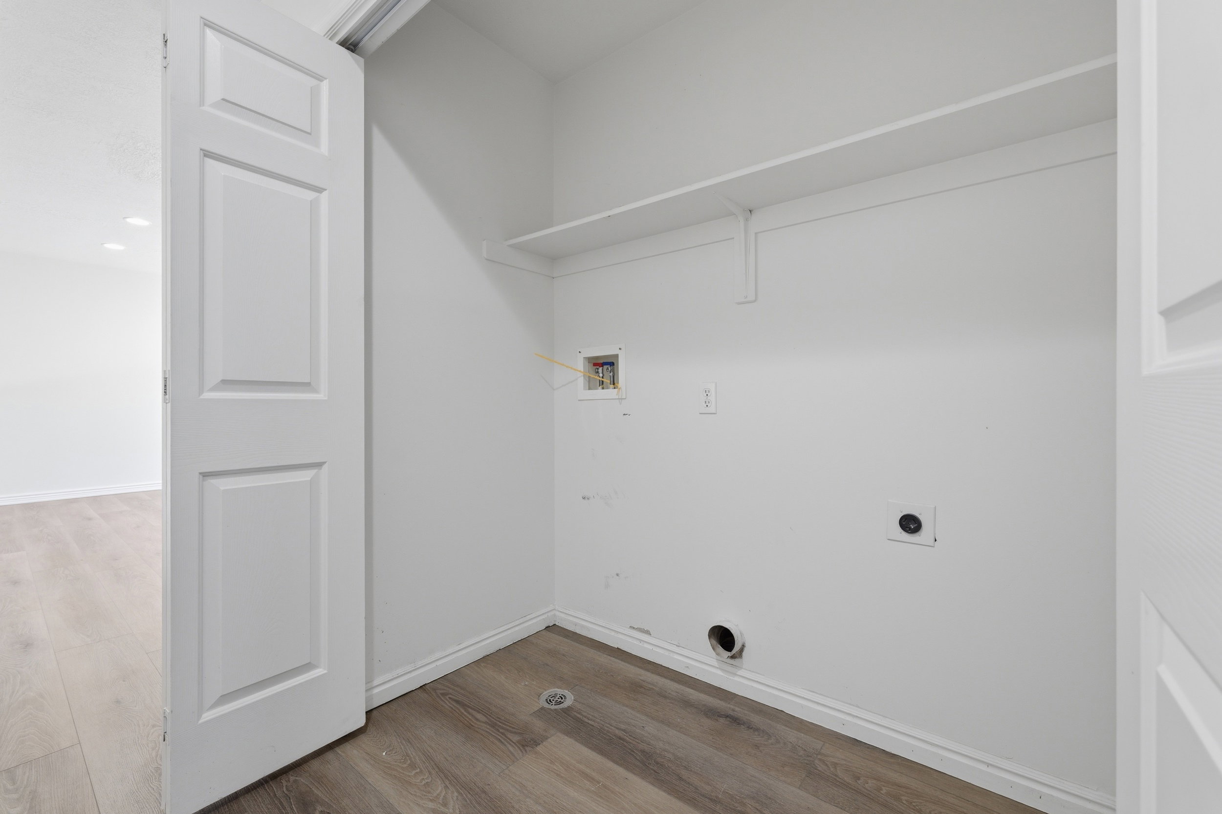 Dedicated laundry closet with wood-finish flooring and integrated shelving