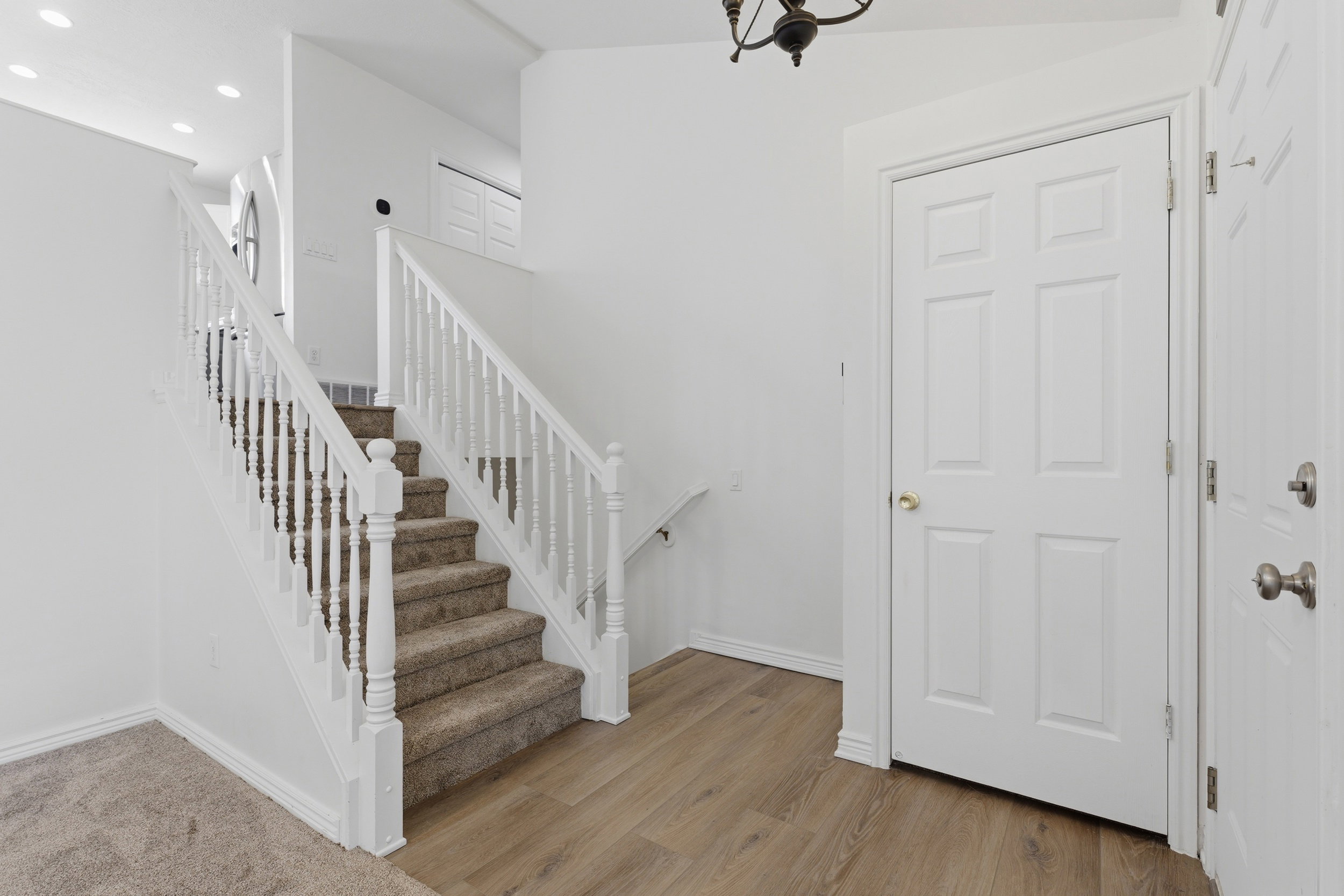 Entryway featuring wood-finish flooring and a carpeted staircase with white balusters