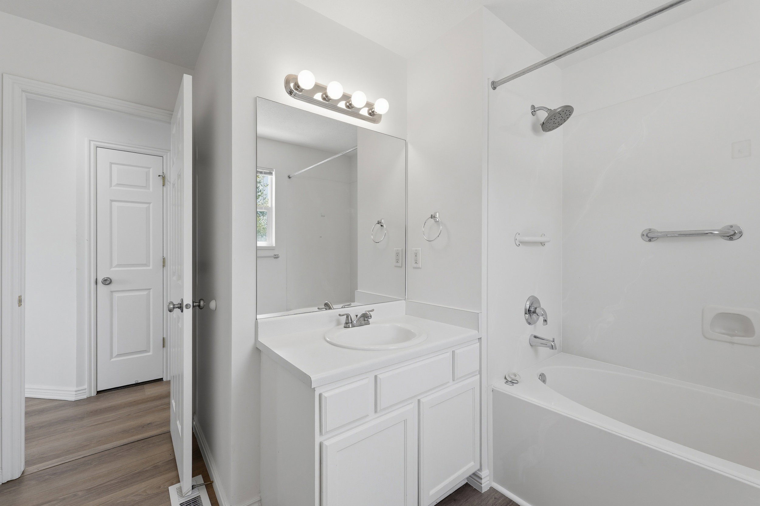 Bathroom featuring a white vanity with a single sink, an integrated countertop, and a large mirror with overhead lighting