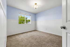 Carpeted spare room with wainscoting