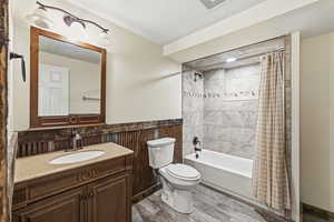 Full bathroom with vanity, shower / bath combo, light wood finished floors, a textured ceiling, and wainscoting