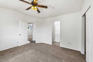 Unfurnished bedroom featuring dark colored carpet, ceiling fan, vaulted ceiling, and a closet