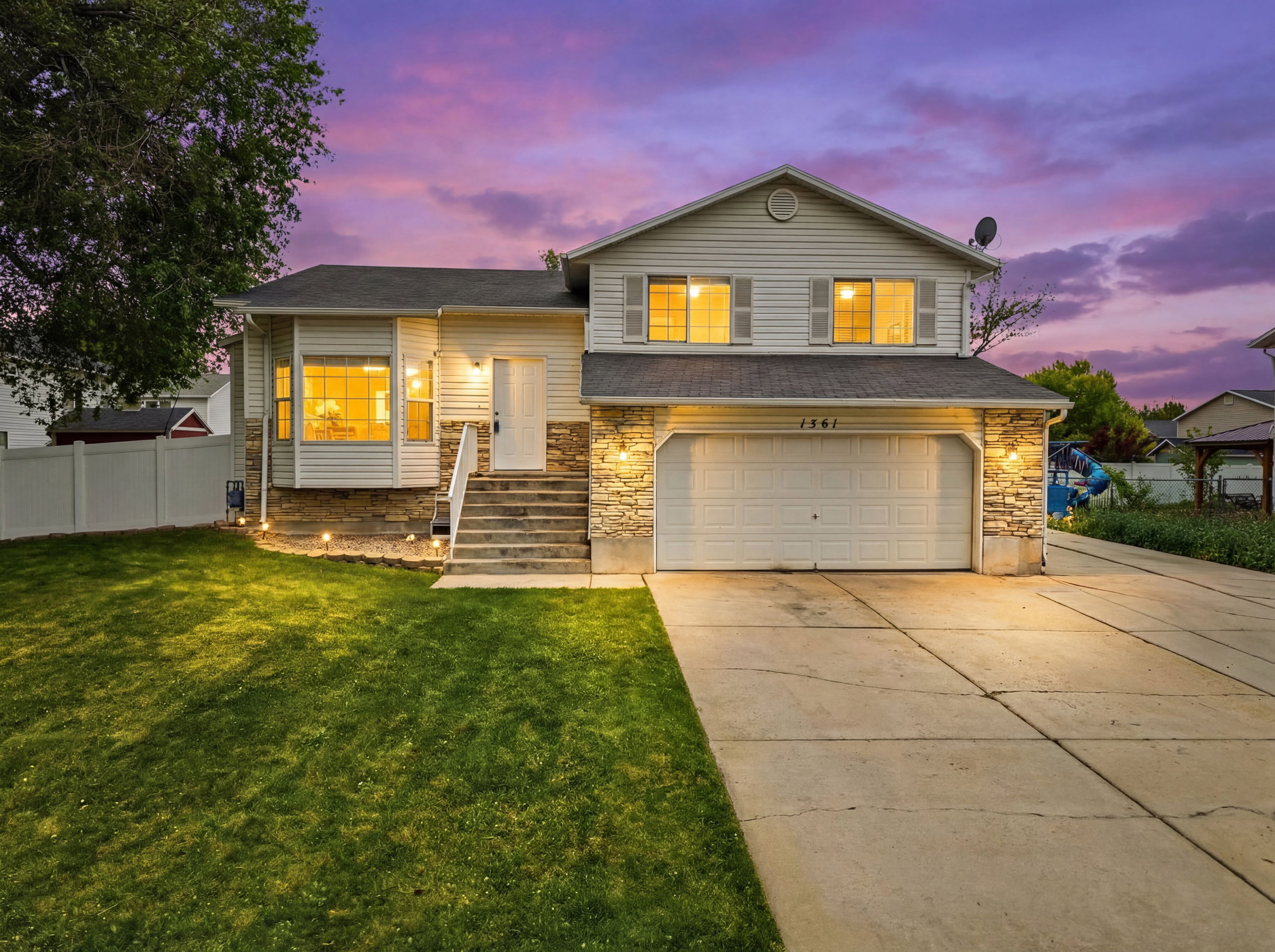 Tri-level home with driveway, an attached garage, and stone siding