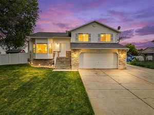 Tri-level home with driveway, an attached garage, and stone siding
