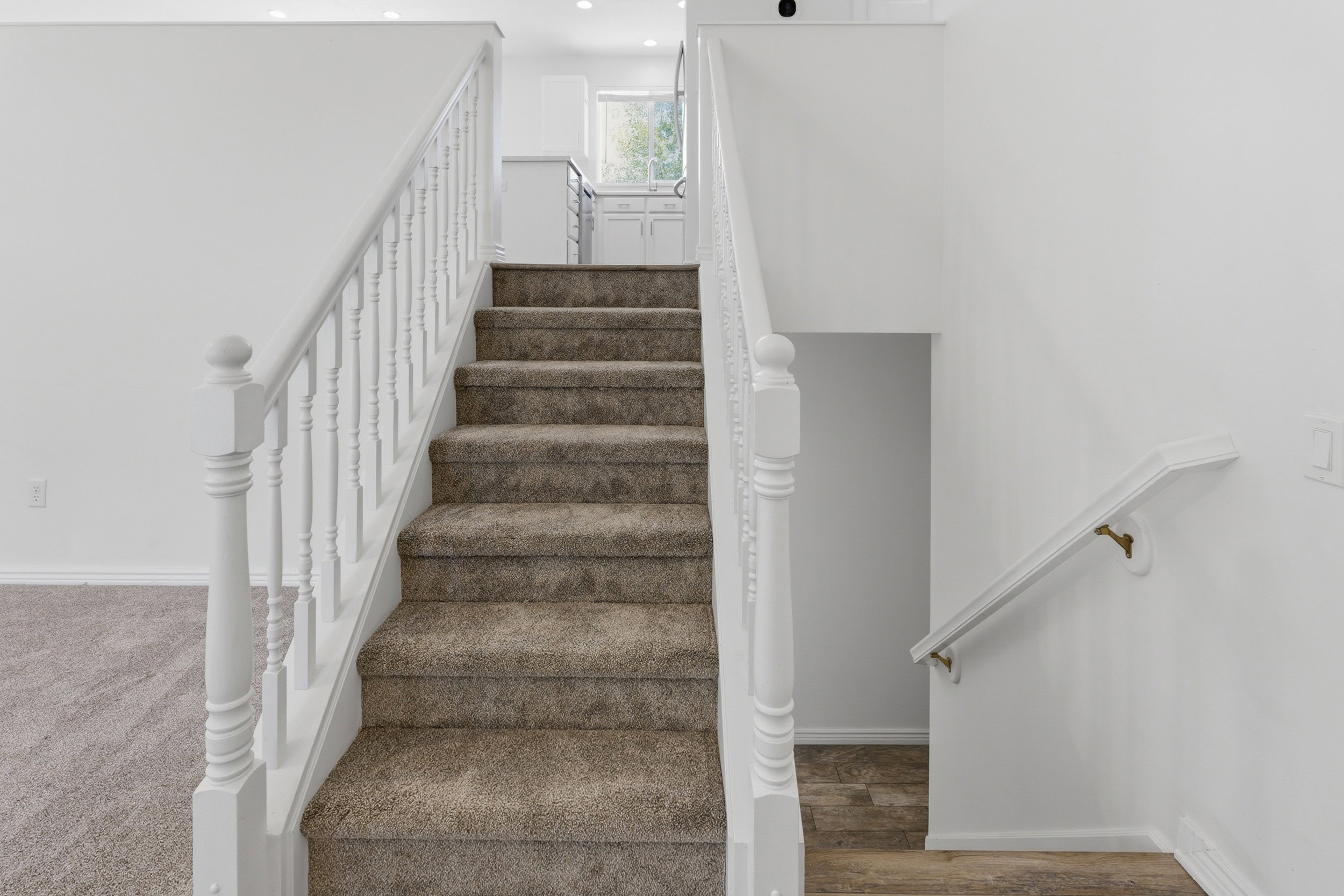 Carpeted staircase with white balusters and handrails