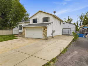 View of front facade featuring stone siding, driveway, and a shingled roof