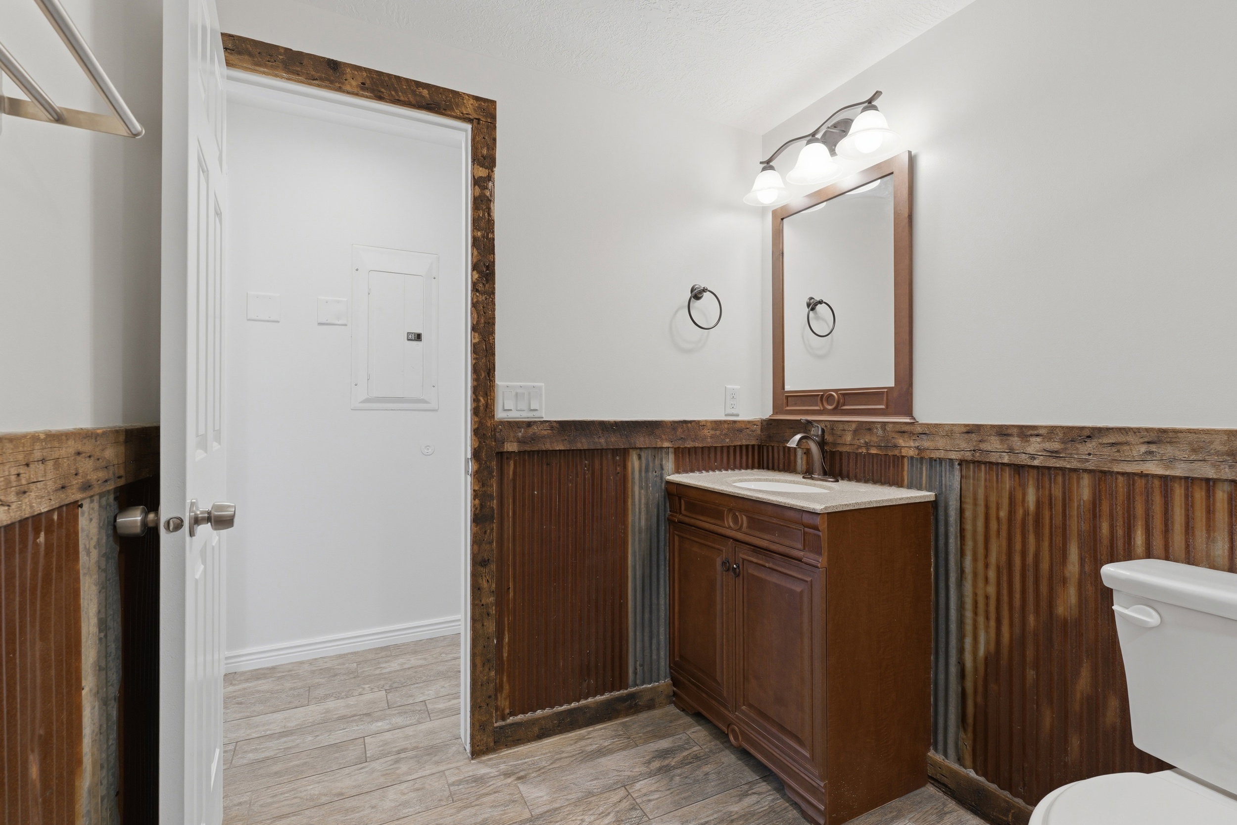 Bathroom featuring a vanity with a white countertop and dark wood-finish cabinetry, a framed mirror, and a three-light fixture
