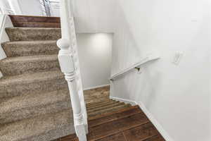 Stairway with wood finished floors and baseboards