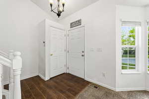 Foyer featuring dark wood finished floors, hanging lights, and lofted ceiling
