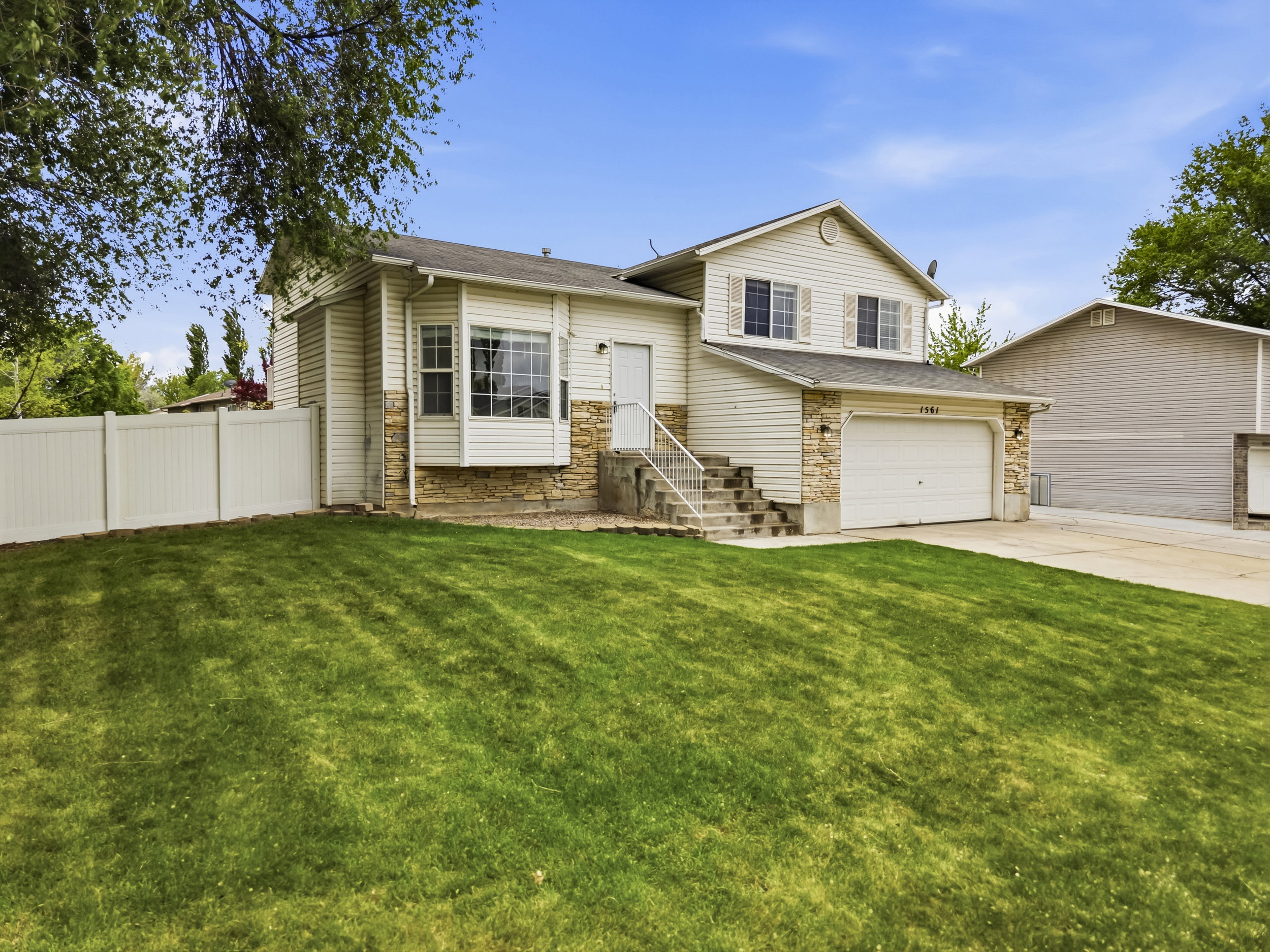 Split level home with stone siding, concrete driveway, a garage, and a shingled roof