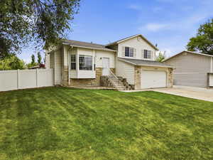 Split level home with stone siding, concrete driveway, a garage, and a shingled roof