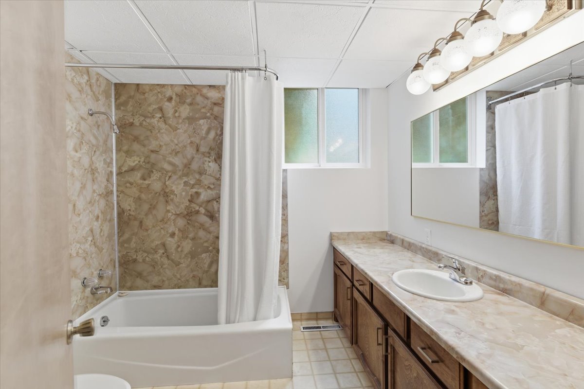 Full bathroom featuring vanity, shower / bath combination with curtain, and a paneled ceiling
