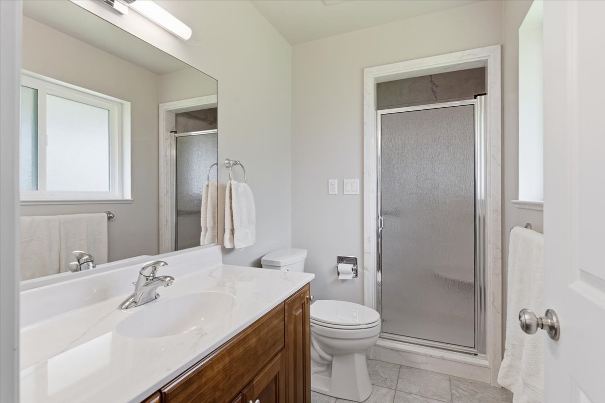Full bathroom with vanity, a shower stall, healthy amount of natural light, and light tile patterned flooring
