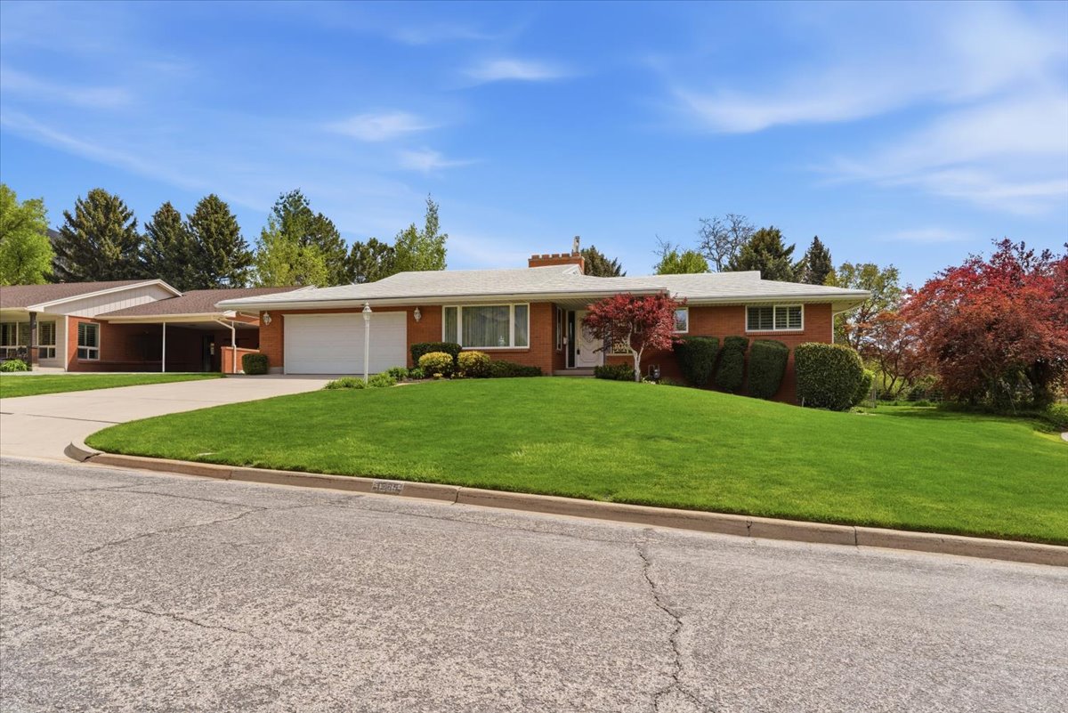 Ranch-style house featuring a front lawn, brick siding, driveway, and a garage
