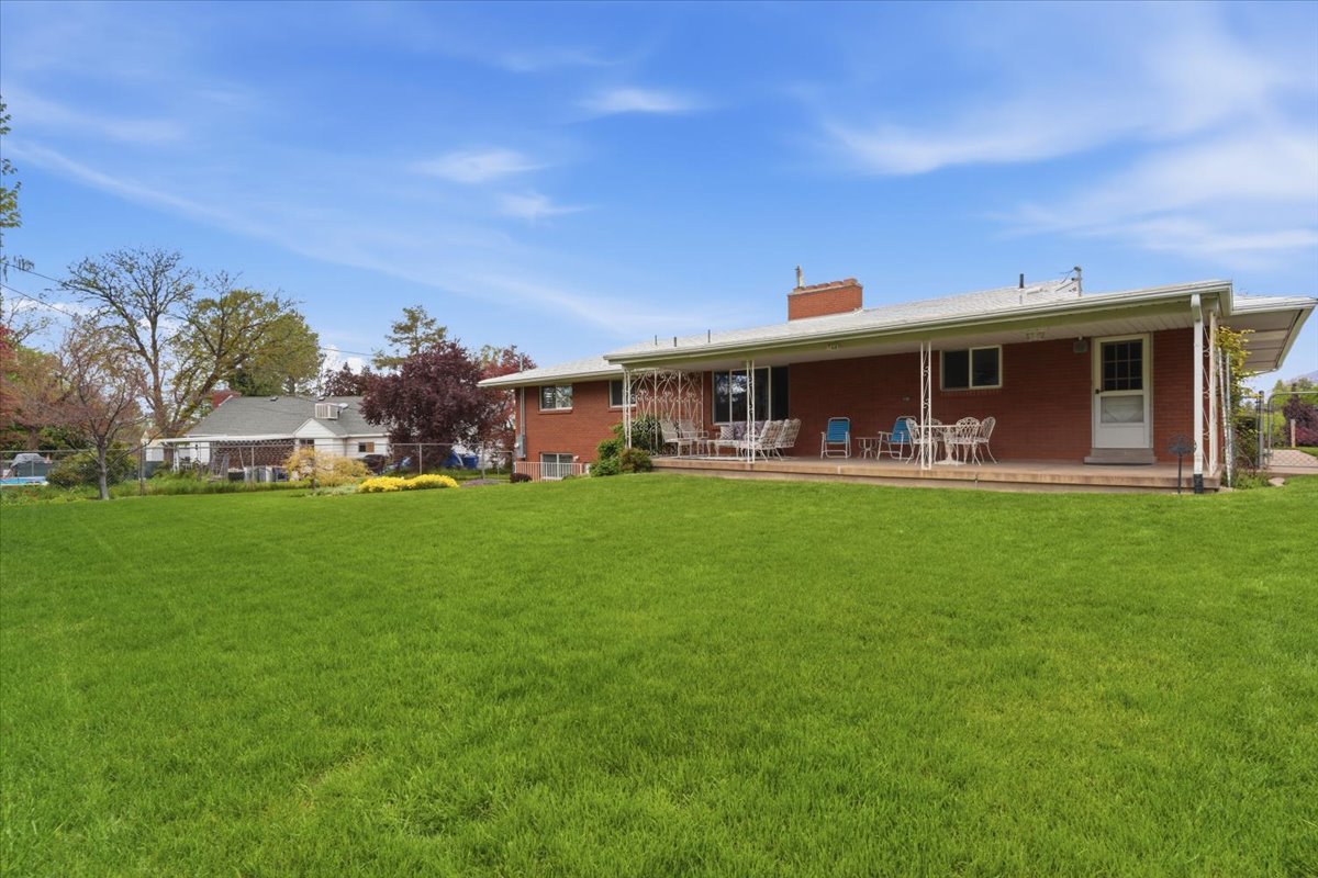 Rear view of house with a chimney, a porch, and brick siding