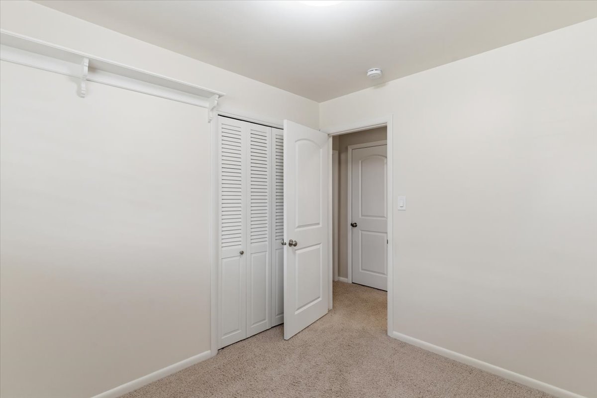 Unfurnished bedroom with light colored carpet and a closet