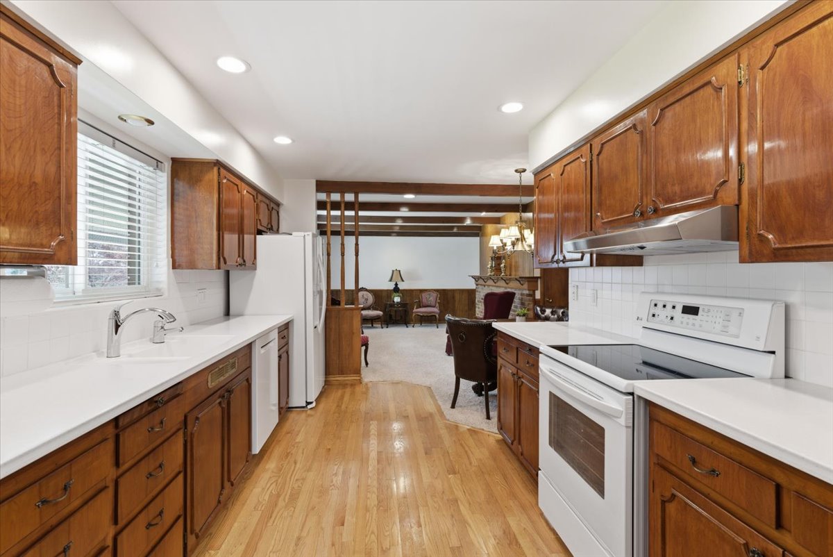 Kitchen with white appliances, wood finish cabinets, and decorative backsplash