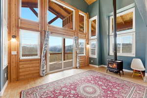 Doorway to outside featuring a wood stove, a mountain view, wood-type flooring, a high ceiling, and healthy amount of natural light
