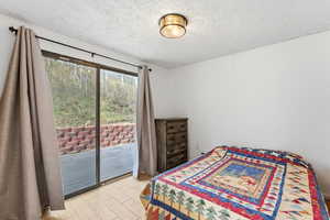 Bedroom with access to exterior, a textured ceiling, and wood finish floors