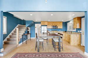 Kitchen with light wood finish cabinetry, recessed lighting, light wood-style floors, stainless steel appliances, and light stone countertops