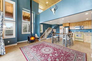Dining room with a wood stove, recessed lighting, light wood-type flooring, and a high ceiling