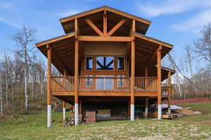 Back of house with a lawn and a deck