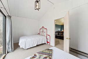 Bedroom featuring a baseboard radiator, light carpet, lofted ceiling, and wood walls