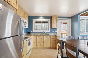 Kitchen with light wood finish cabinetry, stainless steel appliances, light stone counters, light wood-type flooring, and recessed lighting