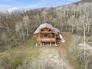 View of front of home with a wooden deck and a view of trees