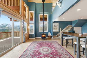 Rec room with a wood stove, a mountain view, a high ceiling, light wood finished floors, and recessed lighting