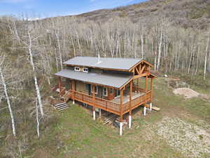 Rear view of property featuring a porch, a metal roof, and a view of trees