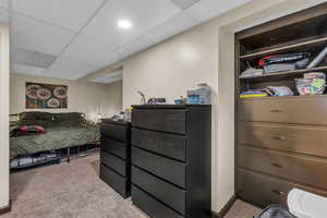 Bedroom with a drop ceiling and light carpet