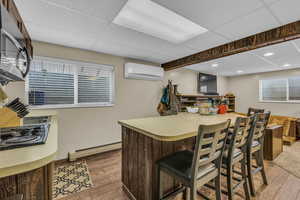 Kitchen with light countertops, dark wood-type flooring, a drop ceiling, a baseboard heating unit, and stainless steel microwave