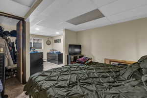 Bedroom with carpet floors, a spacious closet, and a drop ceiling