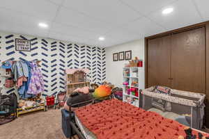 Carpeted bedroom featuring a closet, wallpapered walls, and an accent wall