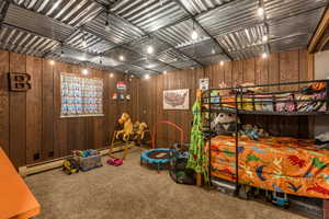 Bedroom with wooden walls, carpet floors, and a baseboard heating unit