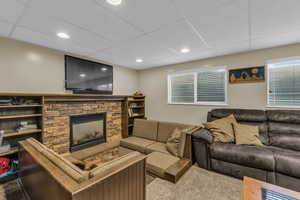 Living room featuring a paneled ceiling, a fireplace, and carpet floors
